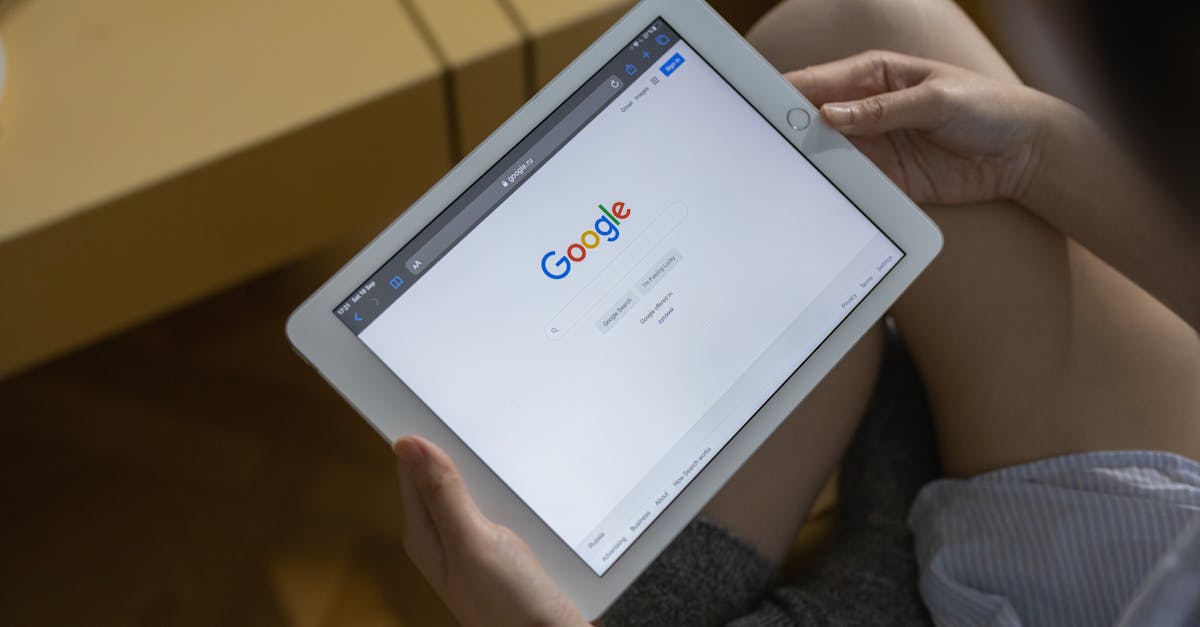 Close-up of hands holding a tablet showing the Google search page.