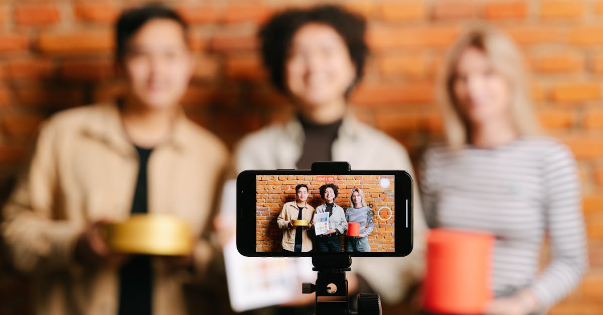 A diverse team of vloggers recording a video with a smartphone against a brick wall backdrop.